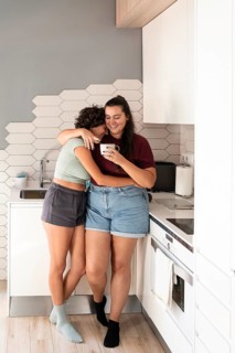 A cheerful lesbian couple shares a coffee break in their stylish kitchen. They enjoy a moment of