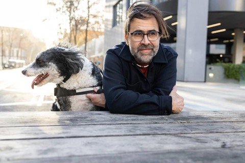A middle-aged man enjoys a quiet moment with his black and white dog while sitting at a wooden
