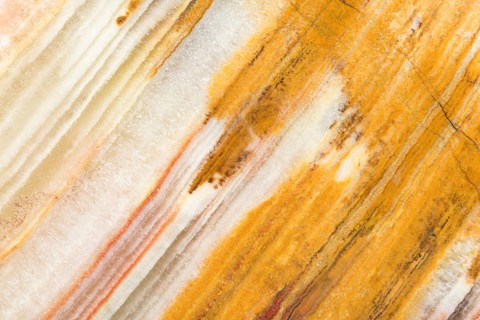 Detailed macro image of layered chalcedony, showcasing its parallel banding in warm golden, cream,