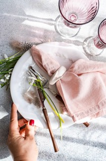 Top view of a cropped unrecognizable woman's hand on an elegant spring table setting featuring