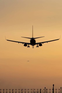 Boeing 737 jet passenger aircraft on approach to land at sunset over landing lights, London