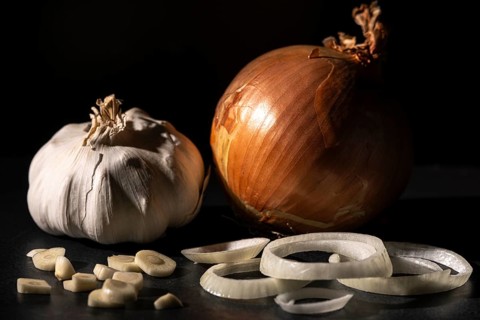 Onion and garlic, cut and whole, dark background