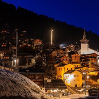 Old farmhouses and barn barn, white cellars, the illuminated cross and the illuminated church tower