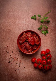 Dried tomatoes, in a bowl, top view, on a brown background