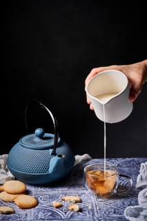 A calming scene with milk being poured into tea from a white jug, surrounded by a traditional