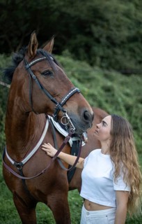 A young woman lovingly interacts with her horse, showcasing a special bond. The pair stands in a