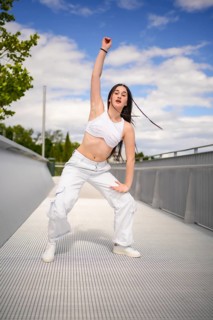 Vertical photo of a caucasian yung urban woman performing dancehall on an outdoor bridge
