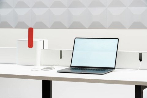 A sleek, minimalist workspace in office features a laptop and smartphone on a white desk, ideal for