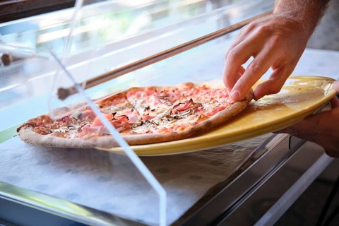 Chef taking freshly baked pizza from oven in restaurant kitchen