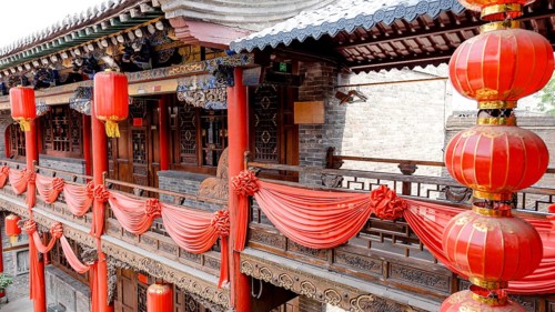 A traditional Chinese building in Pingyao, China, adorned with vibrant red lanterns and drapes. The