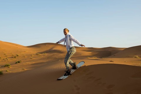 Young woman with snowboard in the sand dunes, near Merzouga, Meknès-Tafilalet region, Erg Chebbi,