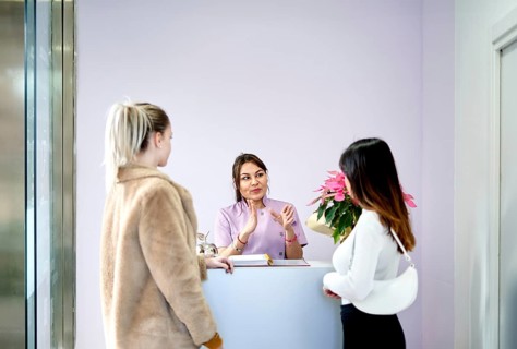 At a busy beauty salon, a staff member warmly engages with clients at the reception desk. The