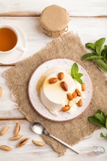 Ricotta cheese with honey and almonds on white wooden background and linen textile. top view, flat