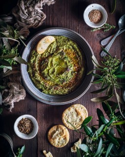 Top view of a rustic setup featuring a bowl of homemade hummus garnished with seeds, surrounded by