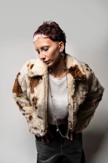 A woman strikes a pose in a stylish faux fur jacket, exuding confidence and boldness. The