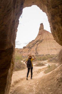 Vertical photo of a woman in summer clothes and hat walking along a path in the desert