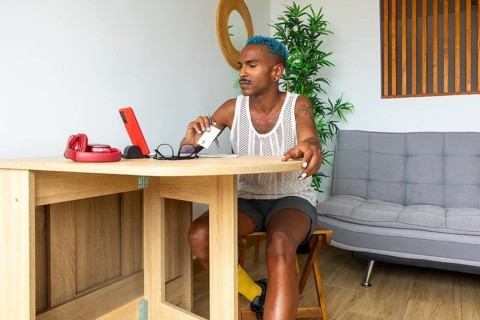 An LGBTQIA+ person with vibrant style is preparing for upcoming holidays, surrounded by festive