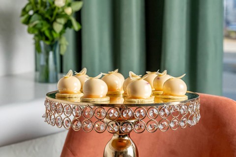 A selection of exquisite vanilla mousse desserts sits on an ornate crystal stand, set against a