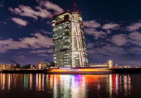 Colourfully illuminated excursion steamer in front of the brightly lit ECB (European Central Bank)