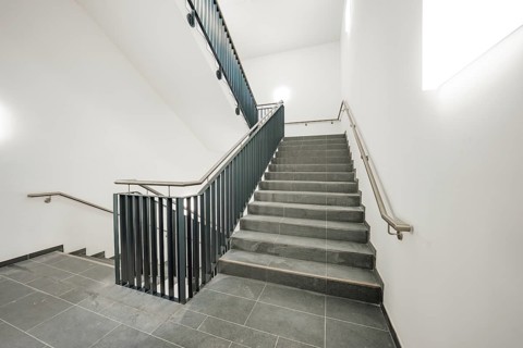 Bright, modern staircase with grey tiles and a simple metal railing, new Calw Hospital, Germany