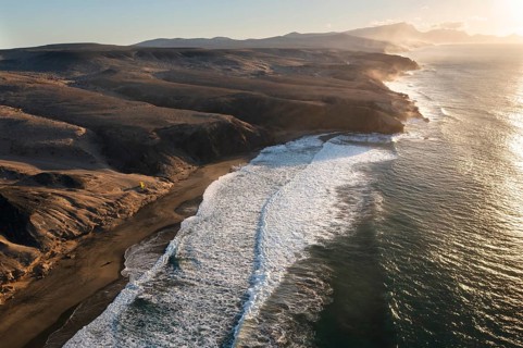 A breathtaking aerial view of the sunset over the serene coastline of Riscos La Pared in