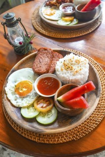 Savoring a vibrant filipino breakfast platter featuring spam, rice, fried egg, fresh fruits, and