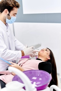 A beautician, wearing a face mask and gloves, gently injects hyaluronic acid into a patient's face