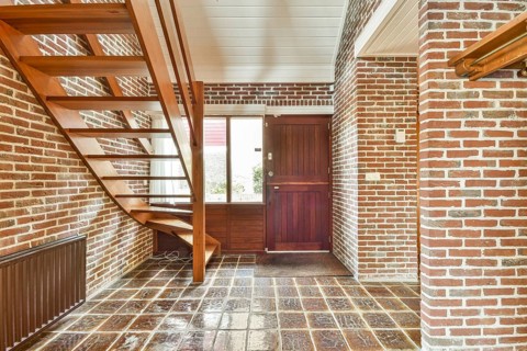 A modern interior showcasing a staircase made of wood, complemented by exposed brick walls,
