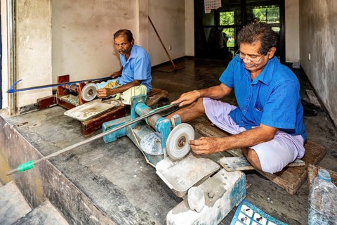 Two men work carefully on machines in a small workshop, the gemstone cutters in the city of