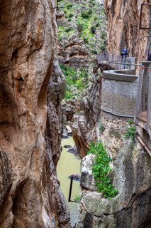 The Caminito del Rey hiking trail along steep rock faces in a picturesque gorge with green