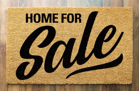 Home For Sale Welcome Mat On A Wood Floor Background