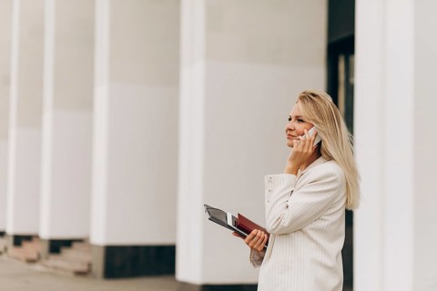 Professional woman standing outside a contemporary office building, engaged in a phone call. She
