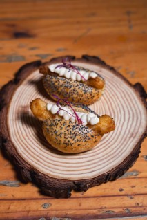 Two mini gourmet buns with poppy seeds, filled with crispy fried bites and topped with smooth cream