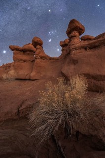 A nighttime scene in Goblin Valley State Park, Utah, featuring unique sandstone formations under a