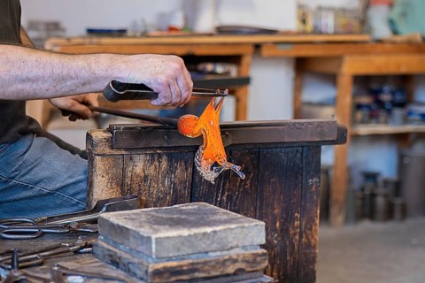 A skilled artisan shapes vibrant molten glass in a traditional workshop, capturing the intricate