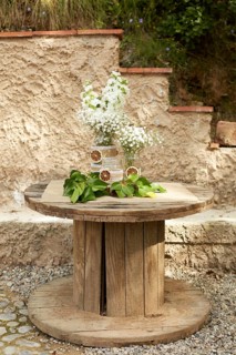 A rustic wooden table features an elegant floral arrangement with white flowers in glass jars.