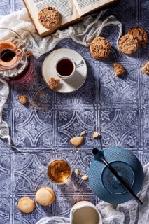 A comforting arrangement featuring a steaming cup of coffee, a pot of tea, chocolate chip cookies,