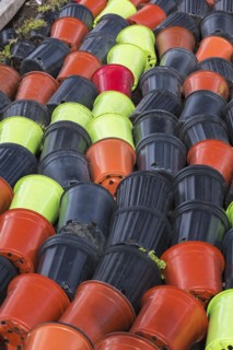 Rows of discarded tipped over red, black and lime green plastic containers on the ground with