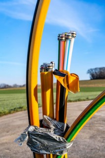 Fibre optic connection, empty conduits protrude from the ground along a dirt track, into which the
