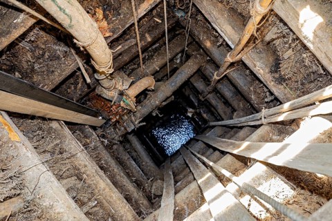 View of a deep wooden well with visible water at the end, The sapphire and gemstone mines at