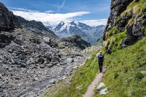 Mountaineer on hiking trail in mountain landscape, descent at Col du Louvie, view of the summit of
