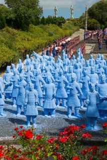 A large number of blue terracotta soldier statues stand on a path lined with flowers, Bacalhôa,