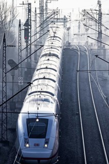 Deutsche Bahn AG tracks with ICE train against the light. Overhead line, signals and infrastructure