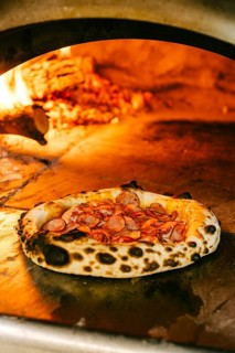 Freshly baked wood-fired pizza topped with smoked pork, salami, pork sausages, chicken fillet,