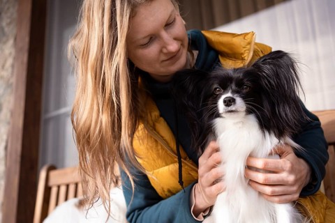 A happy moment captured between a purebreed papillon dog and its owner. The woman lovingly holds