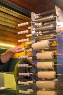 Fresh Baumstriezel being prepared at a Christmas market, with white rolls and warm light,