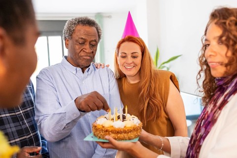 A joyful birthday celebration with friends gathered around a cake. The atmosphere is filled with