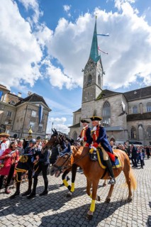 Historically costumed guild members in Zurich's old town, riders in front of the Fraumünster