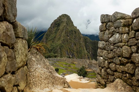 A unique perspective of Machu Picchu, featuring a view through Inca ruins that frame the iconic
