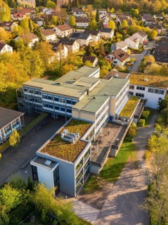 Bird's eye view of a modern architectural complex with green roofs and surrounding houses,
